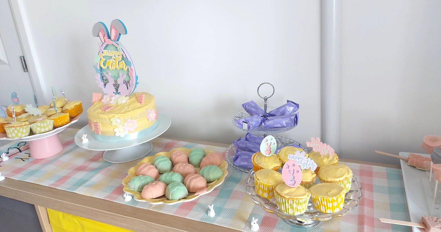 Pastel-colored Easter-themed dessert table with cake, cupcakes, and cookies.
